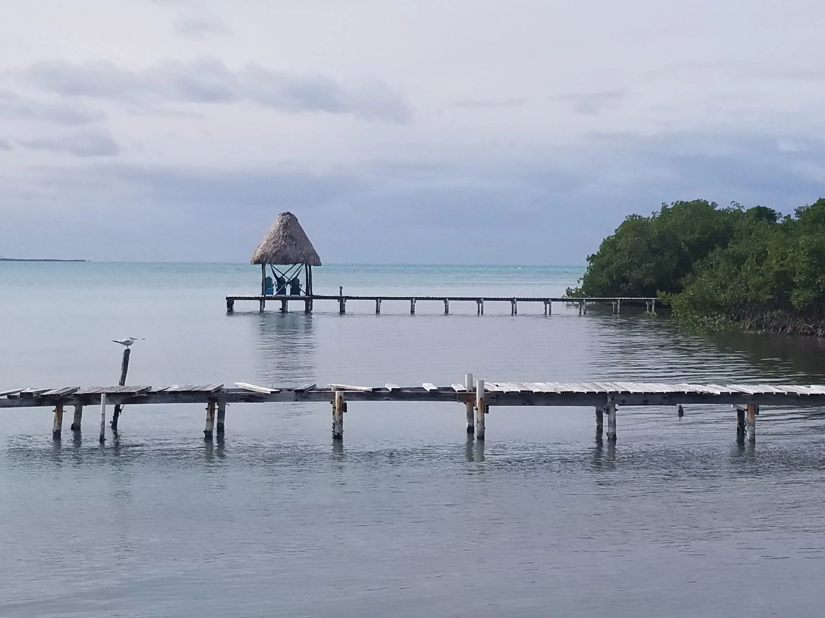 A pier with a hut on it in the middle of water.