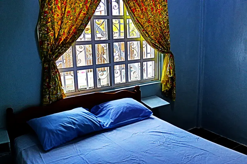 A bed room with a blue bedspread and pillows