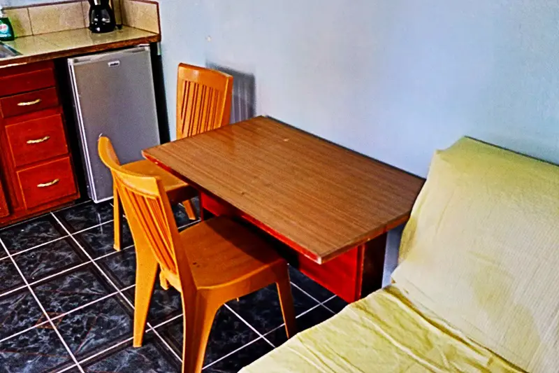 A table and chairs in a room with a bed.