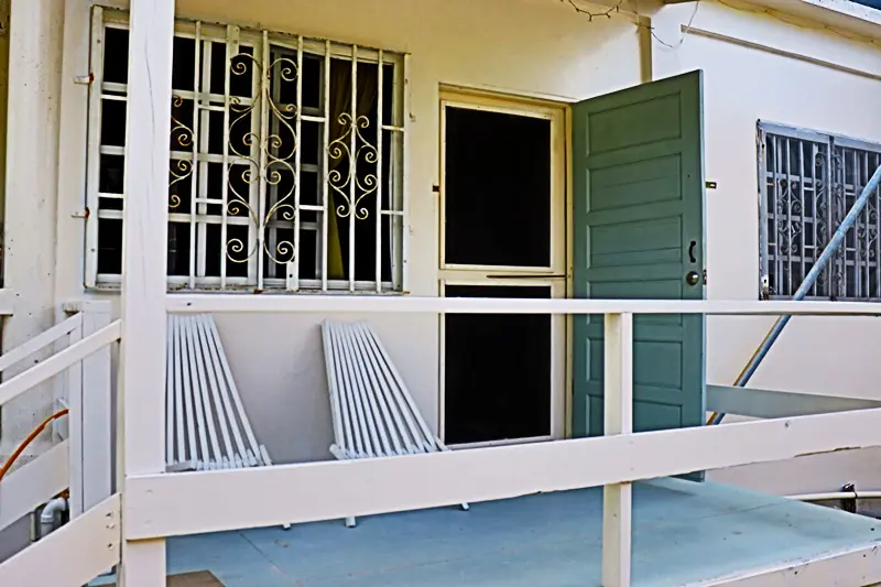 A porch with two chairs and an open door.