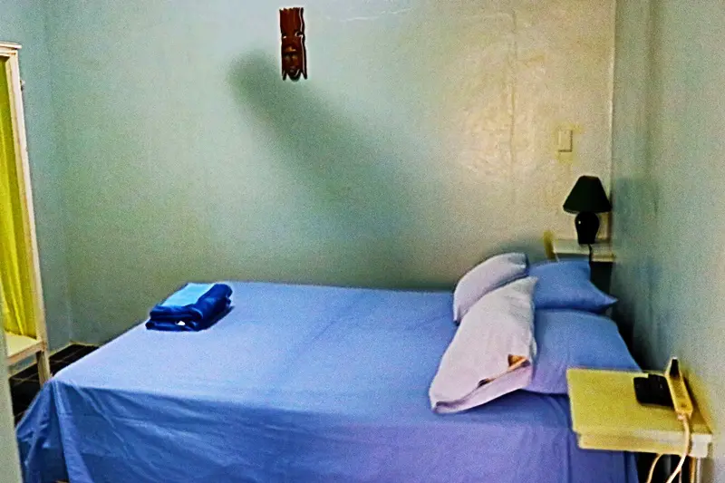 A bed room with a blue bedspread and pillows