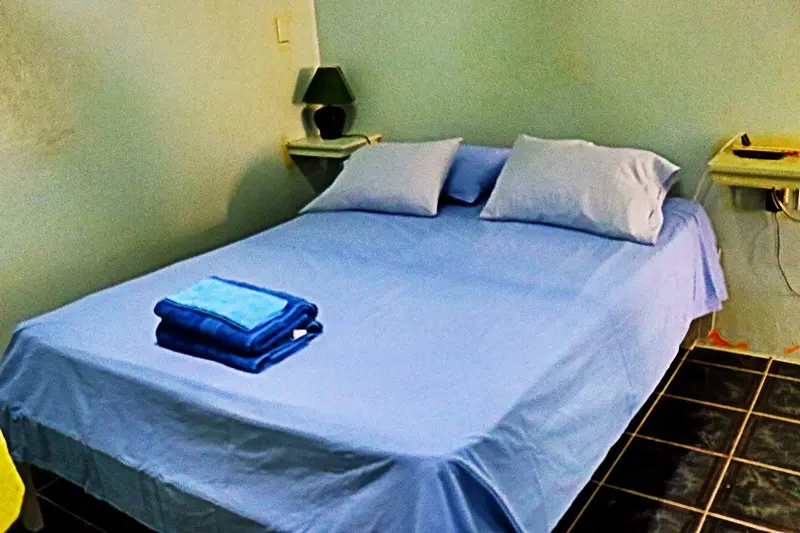 A bed with blue sheets and pillows on it.