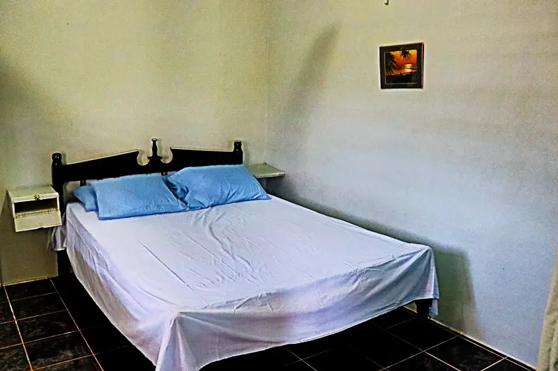 A bed room with a white bed and blue pillows