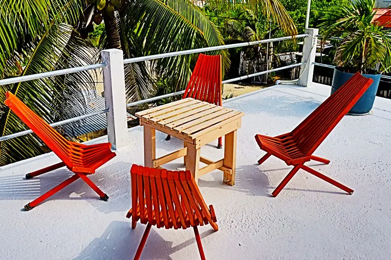 A deck with red chairs and table on it