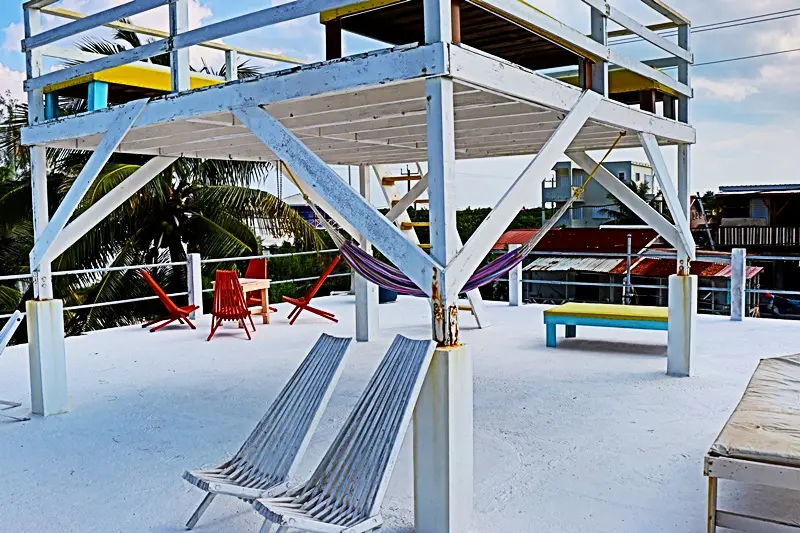 A beach with two lounge chairs and some benches