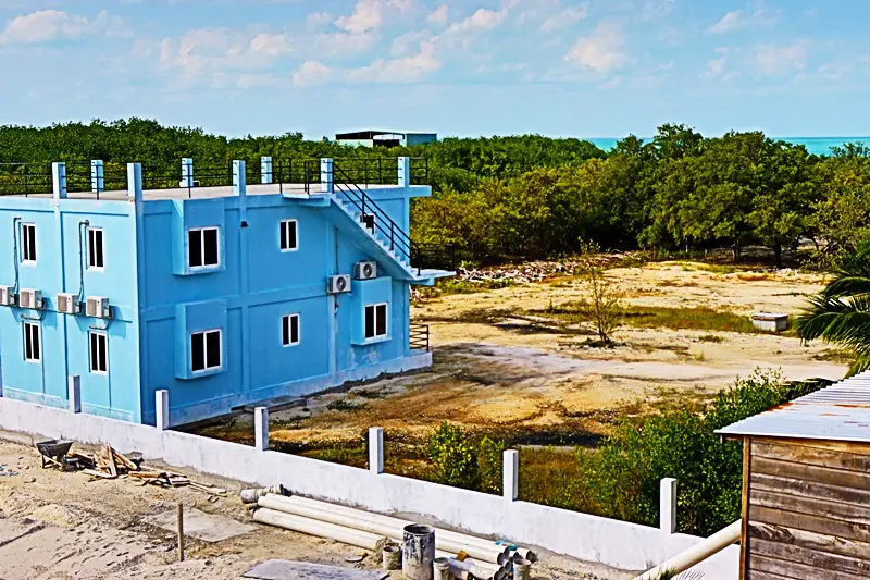 A blue building sitting in the middle of an empty field.