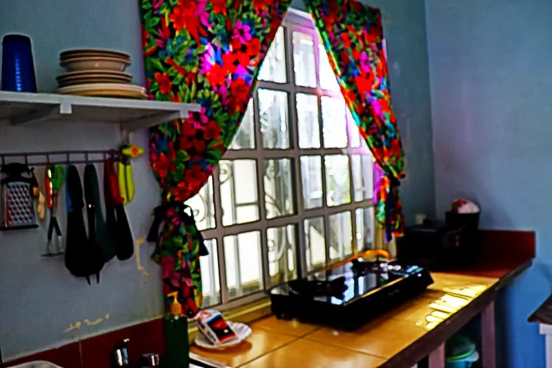 A kitchen window with colorful curtains and a wooden counter.