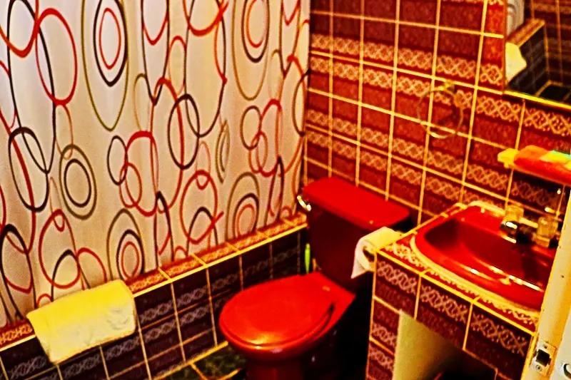 A bathroom with red tiles and a toilet