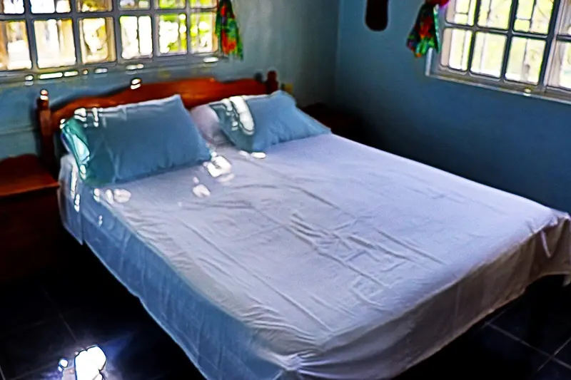 A bed with blue sheets and pillows in a room.