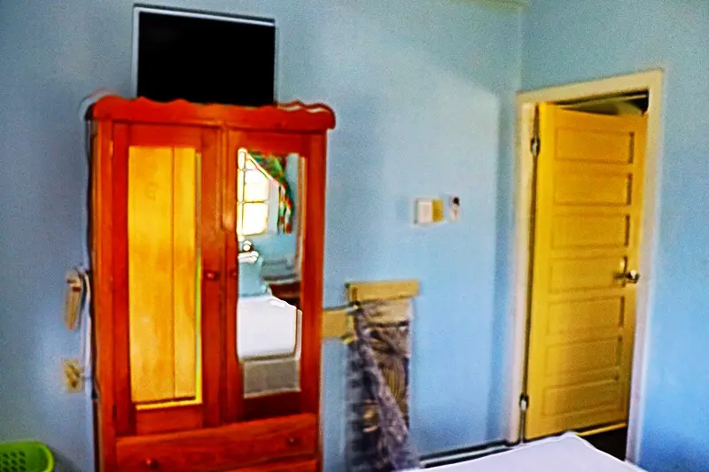 A bedroom with blue walls and wooden furniture.