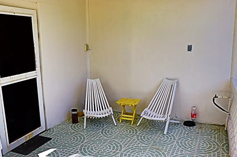 Two white chairs and a yellow table in the corner of room.