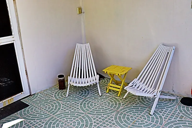 Two white chairs and a yellow table in the corner of room.