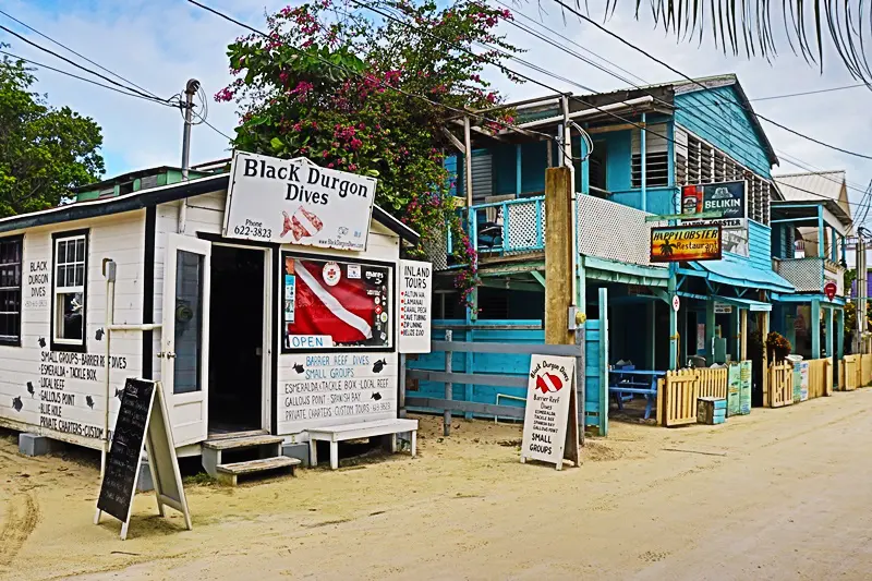 A small dive shop on the beach in front of a building.