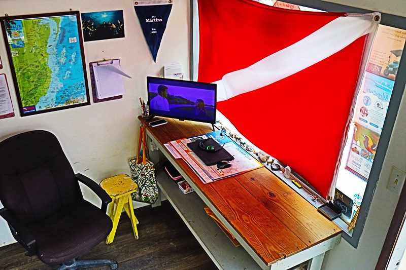 A laptop on top of a desk in front of a flag.