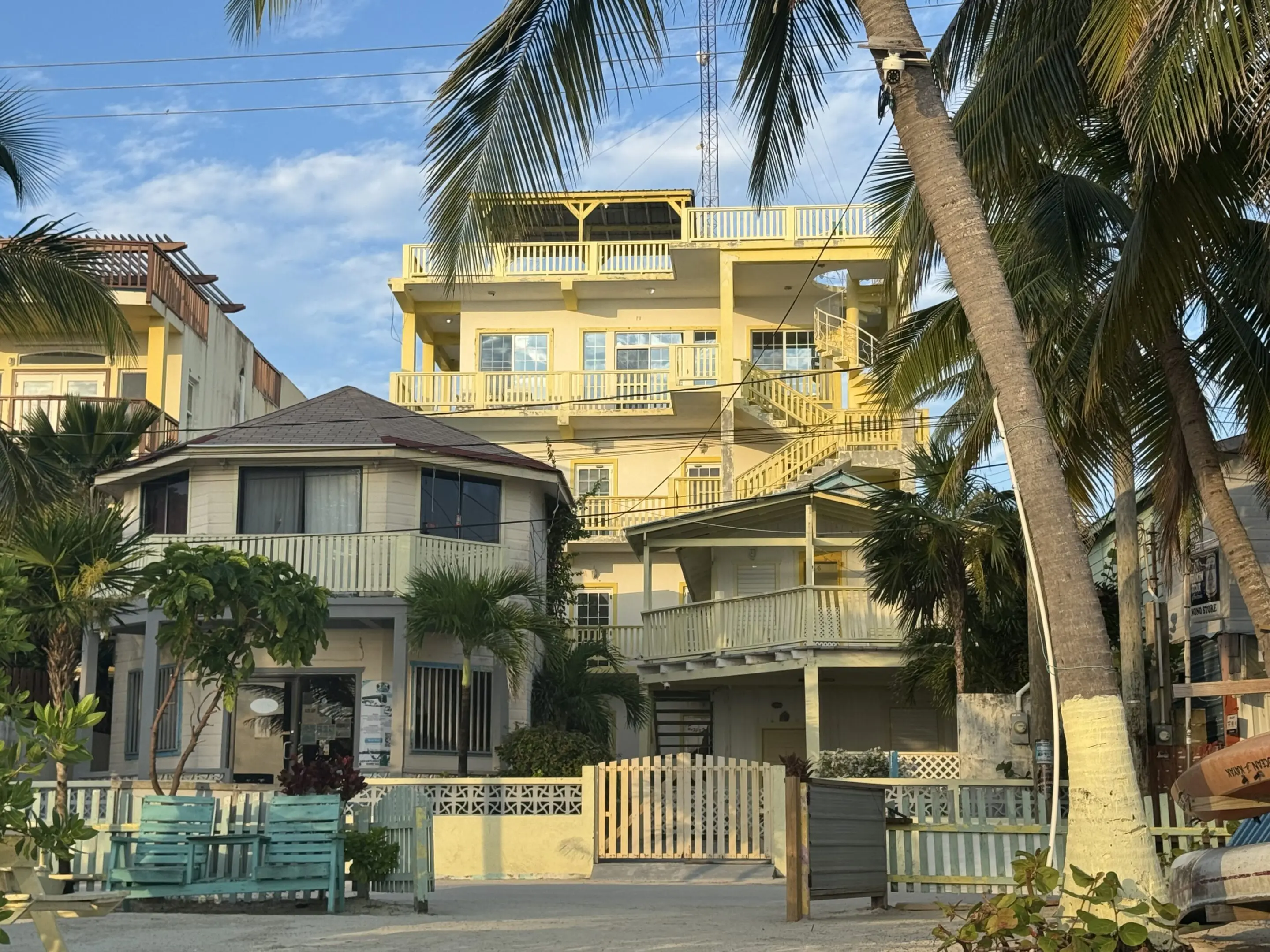 A yellow building with palm trees in front of it.