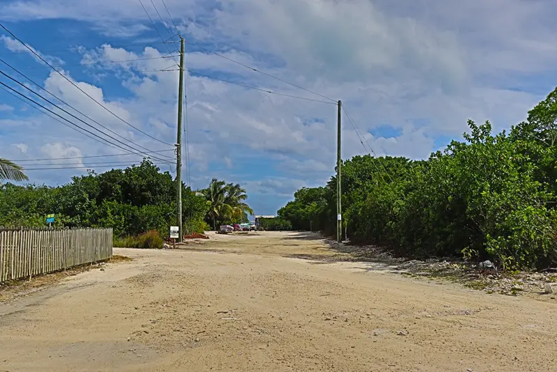 A dirt road with power lines on the side of it.