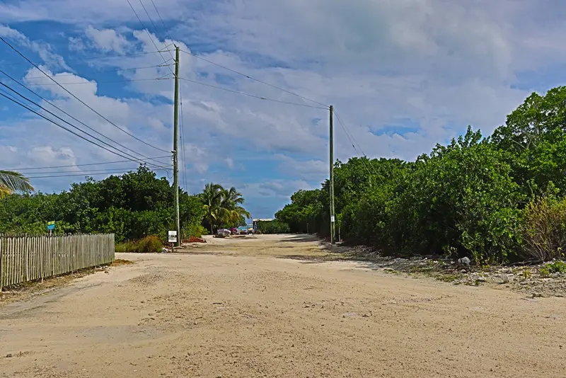 A dirt road with power lines on the side of it.