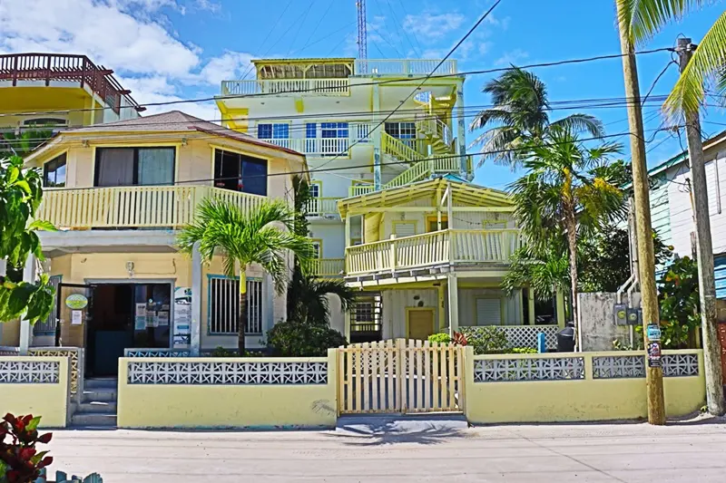 A yellow house with palm trees in front of it.