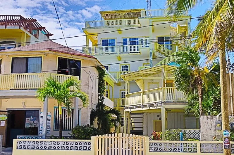 A yellow building with palm trees in front of it.