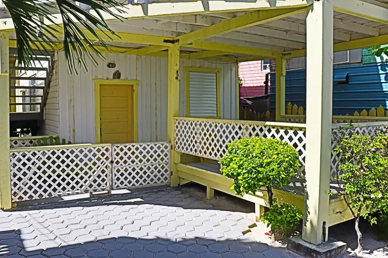 A yellow bench sitting in front of a white building.