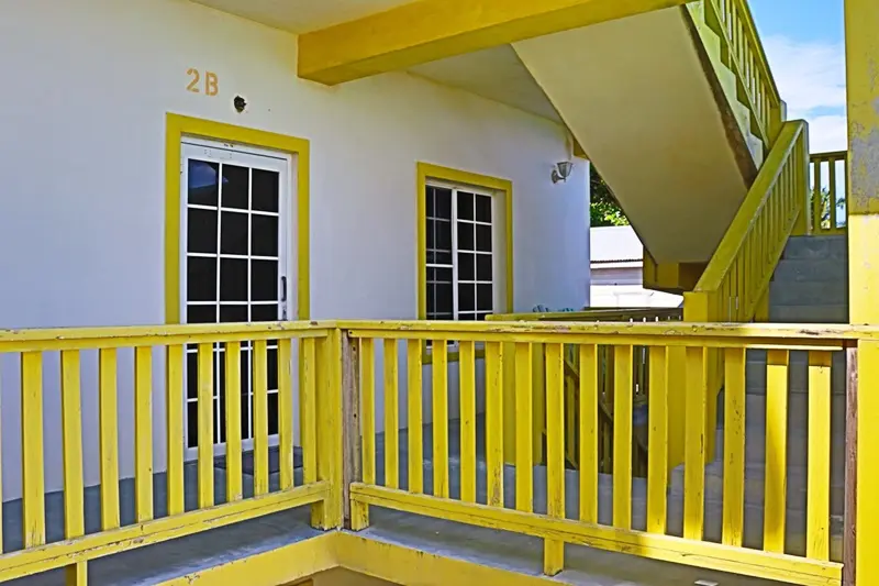 A yellow porch with white walls and wooden railing.