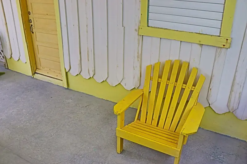 A yellow chair sitting in front of a white wall.