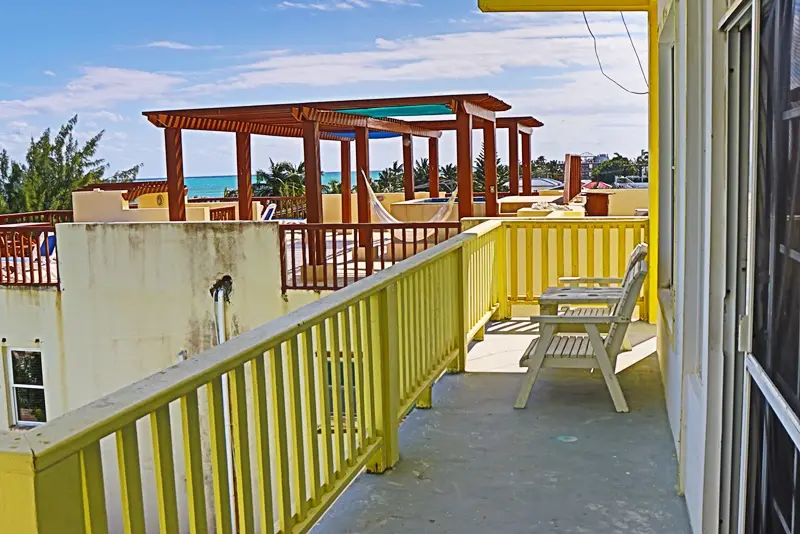 A yellow balcony with a bench and chairs.