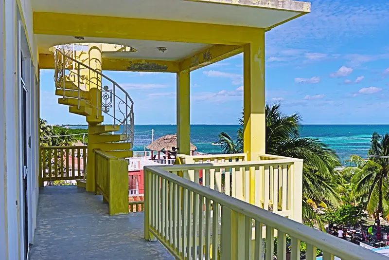 A yellow balcony with stairs leading to the beach.