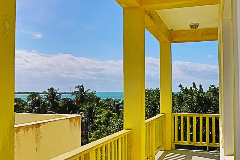 A balcony with yellow walls and a view of the ocean.