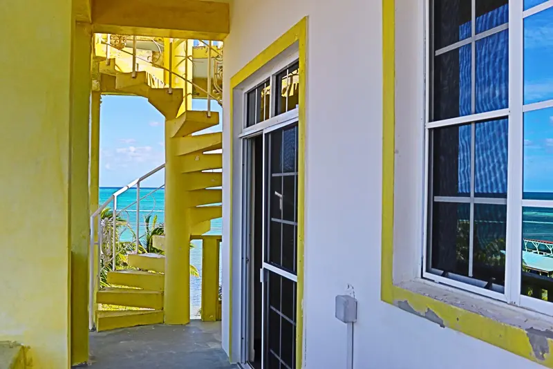 A yellow and white building with stairs leading to the beach.