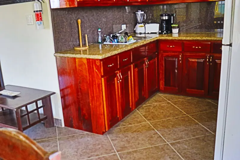 A kitchen with red cabinets and brown tile floors.