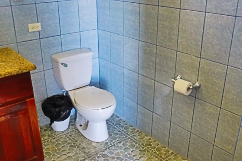 A bathroom with two toilets and a toilet paper holder.