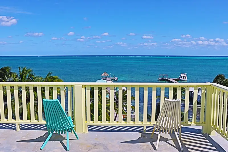 Two chairs on a deck overlooking the ocean.