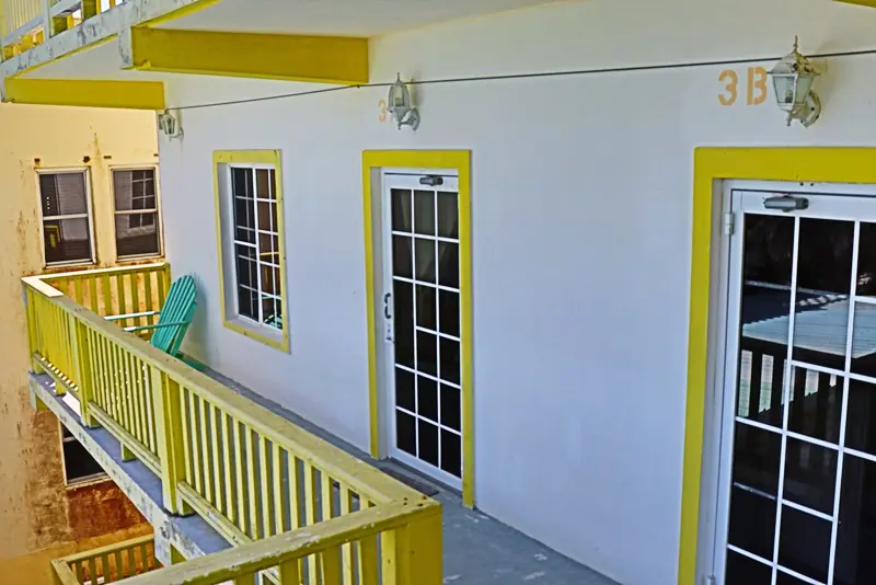 A yellow and white building with two windows.