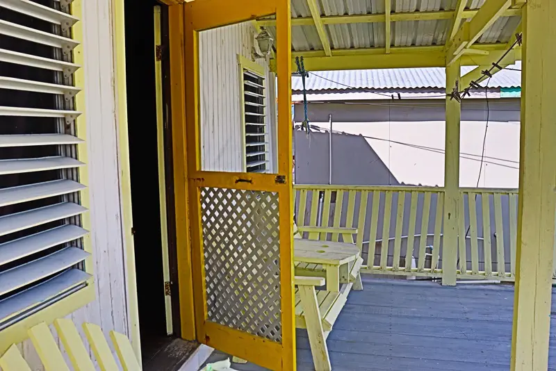 A yellow door on the porch of a house.