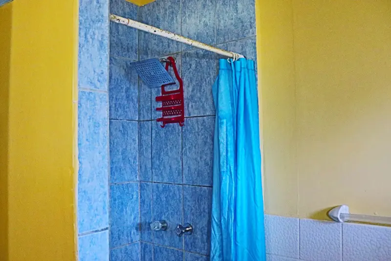 A blue tiled shower with a towel rack.