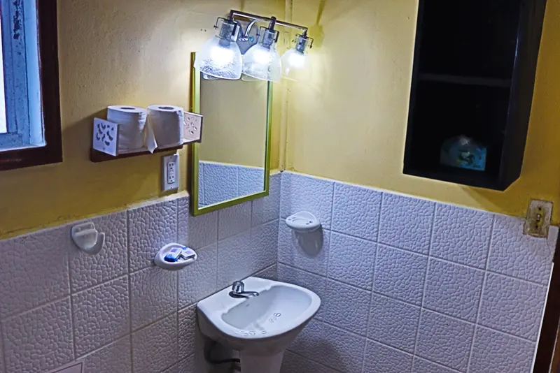 A bathroom with yellow walls and white tile.