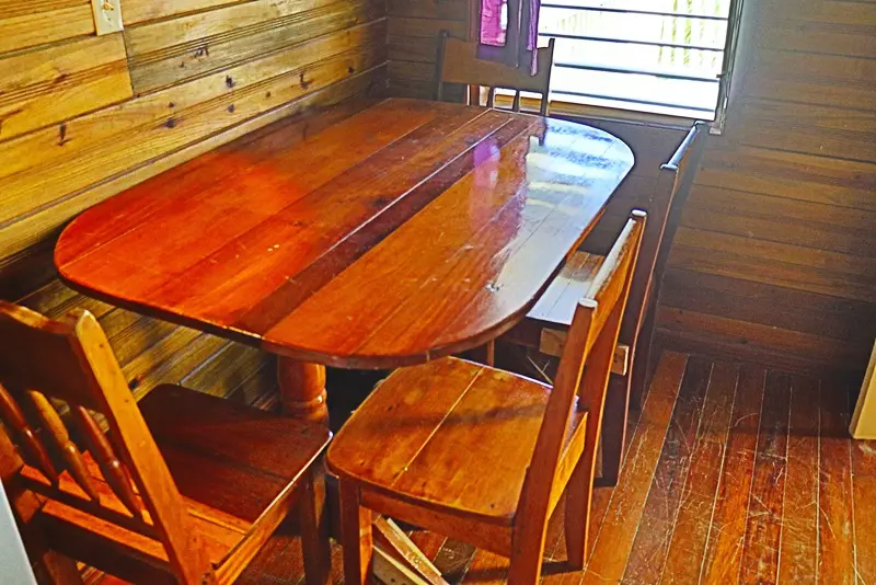 A wooden table with chairs and benches in front of a wall.