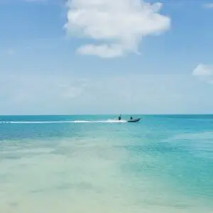 A boat is traveling through the water on the beach.