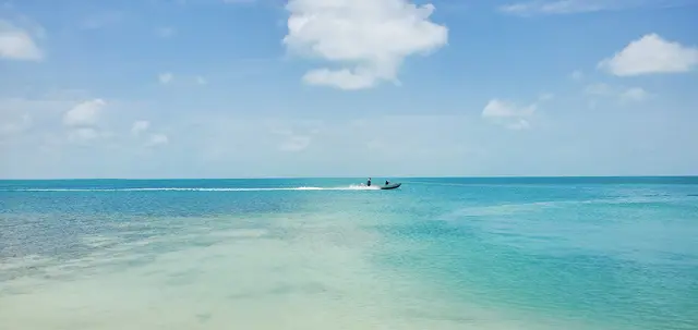 A boat is traveling through the water on the beach.