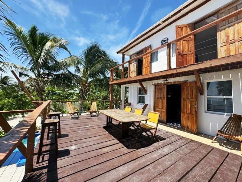 A wooden deck with chairs and tables outside of it