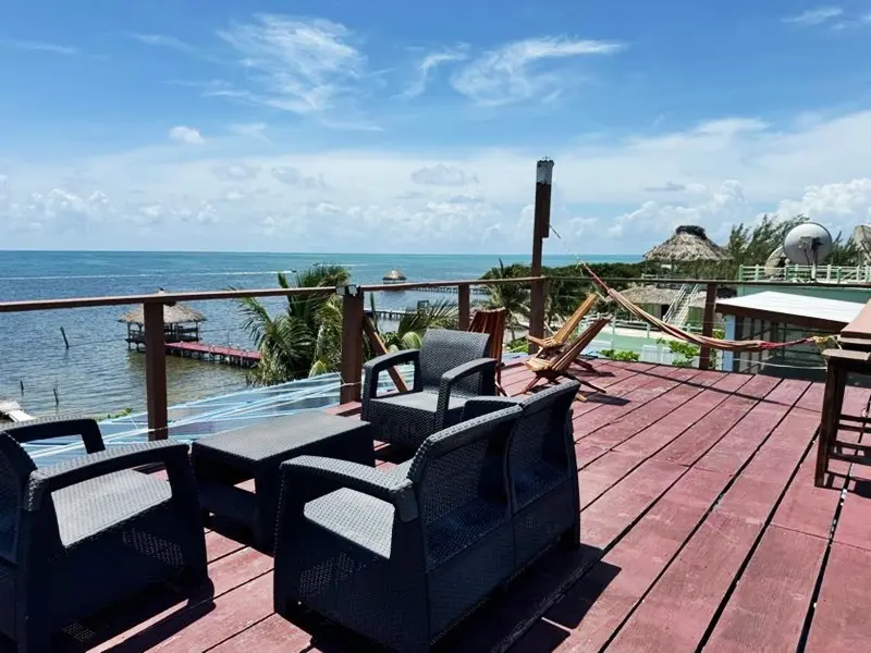 A deck with chairs and tables overlooking the ocean.