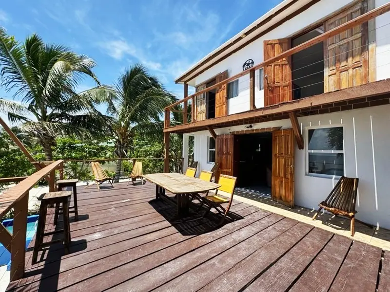 A wooden deck with chairs and tables outside of it