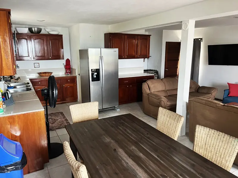 A kitchen with a table and chairs, refrigerator, microwave, oven, and coffee maker.