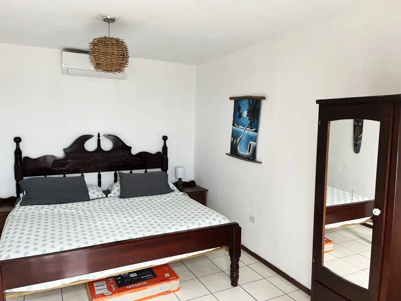 A bedroom with a bed, dresser and mirror.