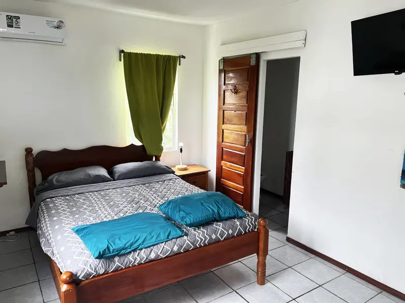 A bedroom with a bed, nightstand and door.