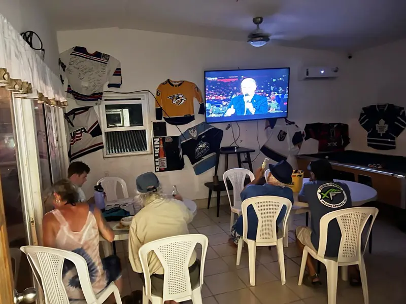 A group of people sitting around in chairs watching television.