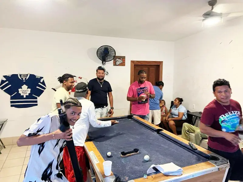 A group of people standing around a pool table.