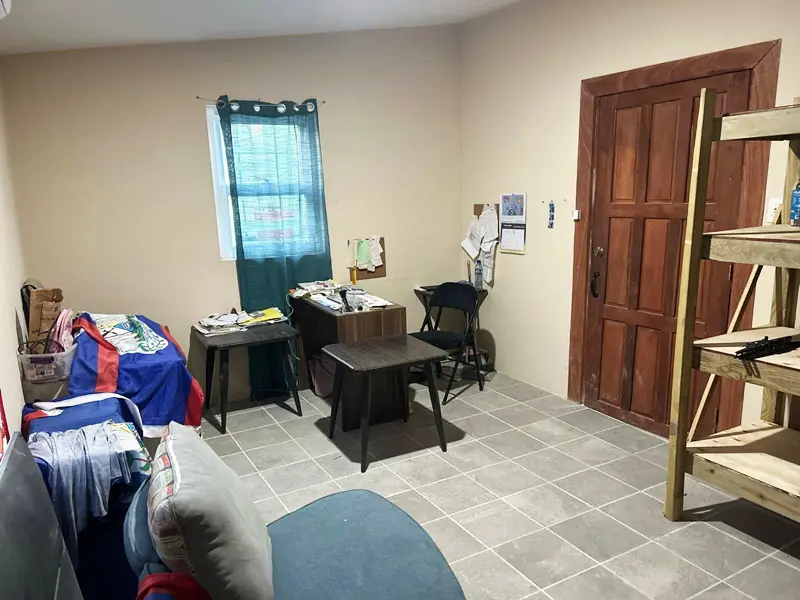 A room with two tables and chairs, a desk and a door.