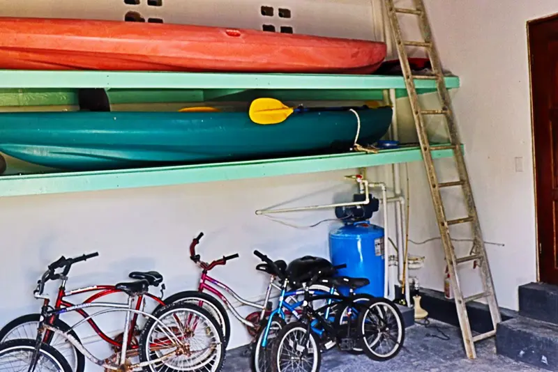 A ladder in the middle of two shelves with bicycles and boats.